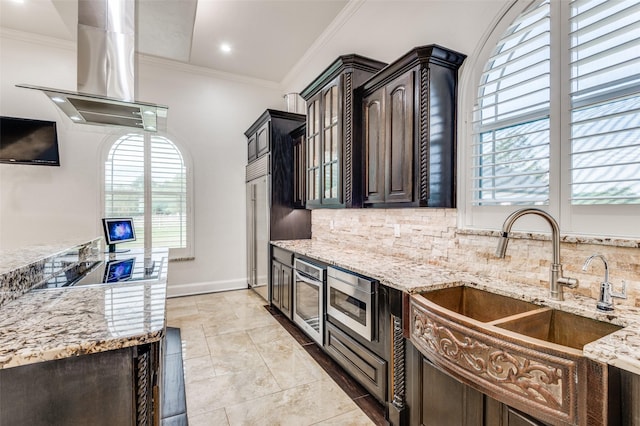 kitchen featuring light stone countertops, dark brown cabinets, sink, and stainless steel microwave