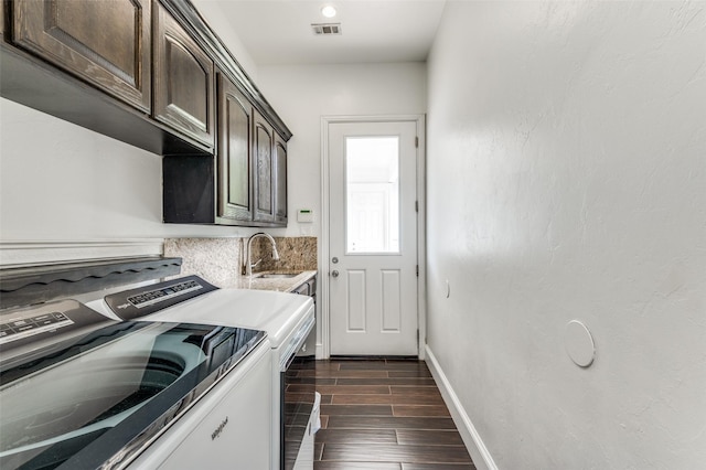 laundry room with washing machine and clothes dryer, sink, cabinets, and dark hardwood / wood-style floors