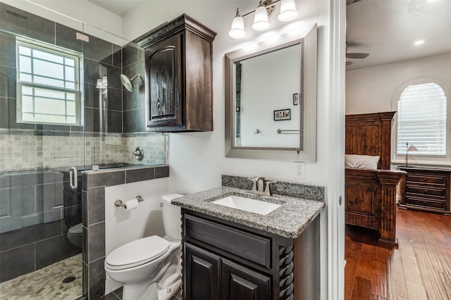 bathroom with vanity, ceiling fan, hardwood / wood-style floors, toilet, and a shower with shower door