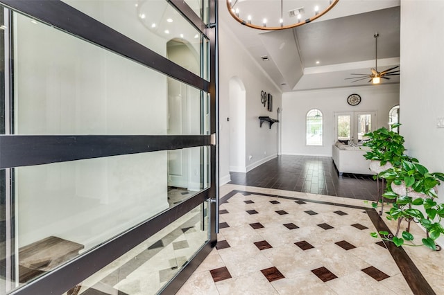 foyer entrance featuring a raised ceiling, ceiling fan, and french doors