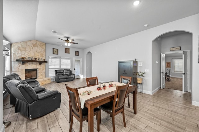 dining room with lofted ceiling, a stone fireplace, and ceiling fan