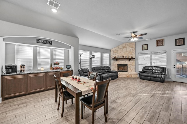 dining area featuring ceiling fan, lofted ceiling, and a fireplace