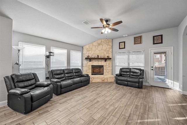 living room featuring lofted ceiling, a fireplace, light hardwood / wood-style floors, and ceiling fan