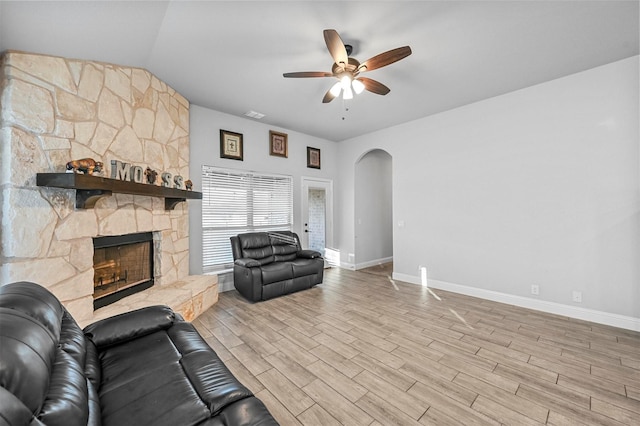 living room with ceiling fan, a fireplace, vaulted ceiling, and light hardwood / wood-style flooring