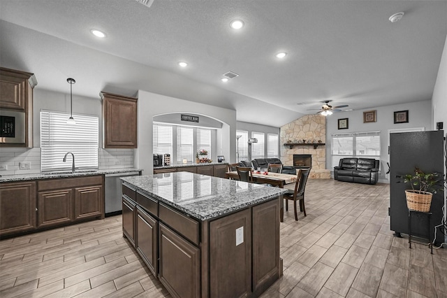 kitchen featuring pendant lighting, a fireplace, dishwasher, sink, and a center island