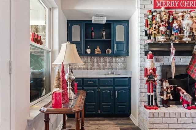 bar featuring dark hardwood / wood-style flooring, sink, blue cabinets, and backsplash