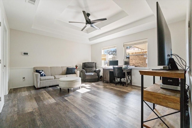 living room with a tray ceiling, ceiling fan, and dark hardwood / wood-style floors