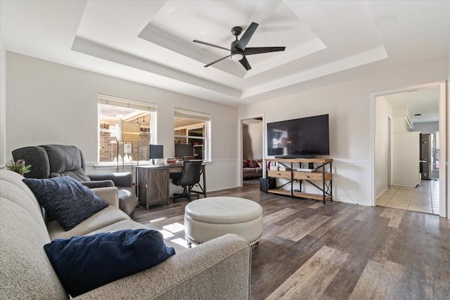 living room with a raised ceiling, ceiling fan, and hardwood / wood-style floors