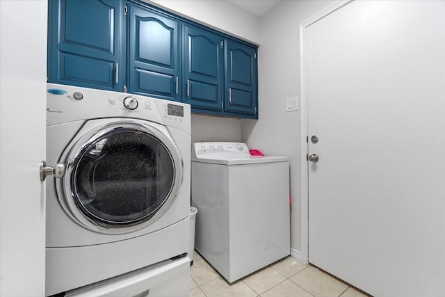 laundry area featuring washer and clothes dryer, light tile patterned flooring, and cabinets