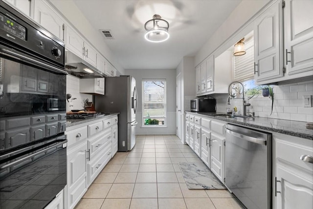 kitchen featuring white cabinetry, sink, stainless steel appliances, backsplash, and dark stone countertops