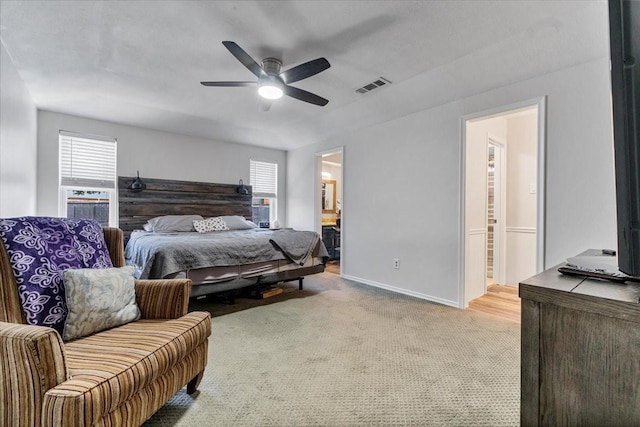 bedroom with ensuite bath, ceiling fan, light colored carpet, and multiple windows