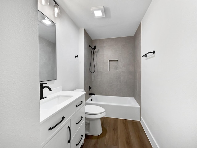 full bathroom featuring hardwood / wood-style flooring, tiled shower / bath, vanity, and toilet