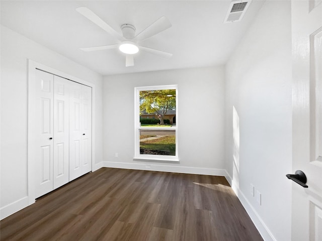 unfurnished bedroom featuring dark wood-type flooring, a closet, and ceiling fan