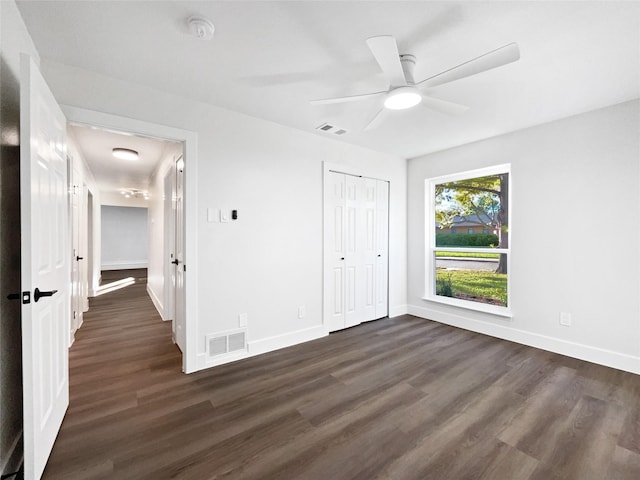 unfurnished bedroom with dark wood-type flooring, a closet, and ceiling fan