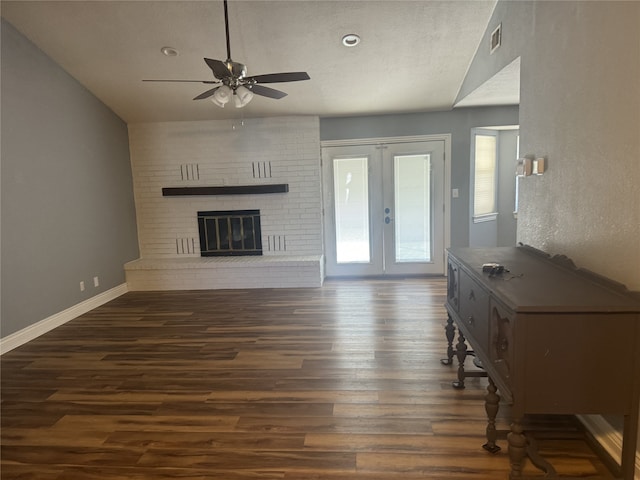 unfurnished living room with ceiling fan, french doors, a brick fireplace, dark hardwood / wood-style flooring, and vaulted ceiling