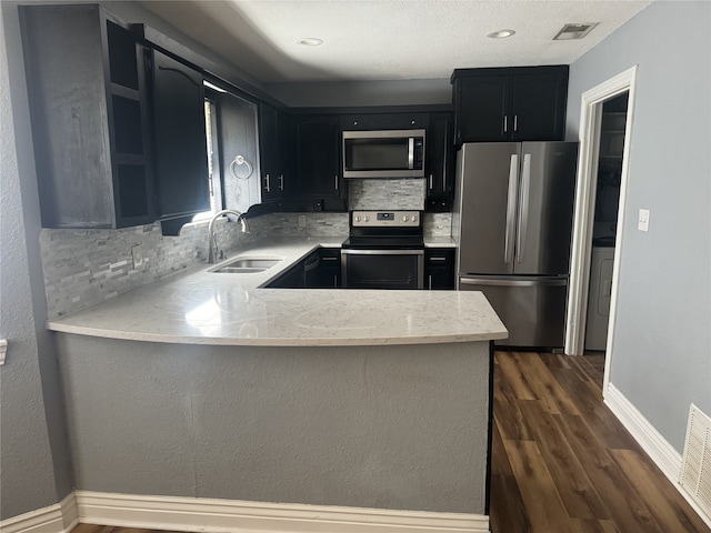 kitchen with kitchen peninsula, decorative backsplash, stainless steel appliances, sink, and dark hardwood / wood-style floors