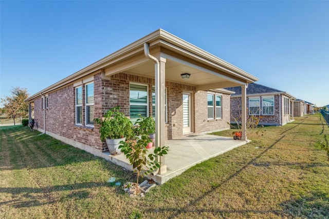 back of property with a lawn and a patio area