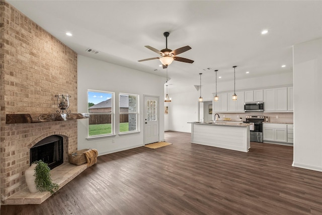 unfurnished living room featuring a fireplace, ceiling fan, dark hardwood / wood-style flooring, and sink