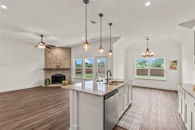 kitchen with a brick fireplace, dishwasher, dark hardwood / wood-style floors, white cabinetry, and hanging light fixtures