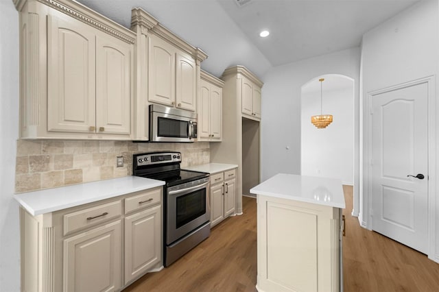 kitchen featuring light hardwood / wood-style floors, appliances with stainless steel finishes, a kitchen island, and tasteful backsplash