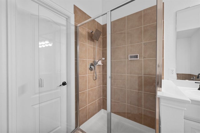 bathroom featuring a shower with door and vanity