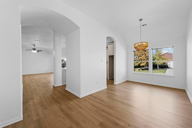 unfurnished room with ceiling fan with notable chandelier, light hardwood / wood-style flooring, and lofted ceiling