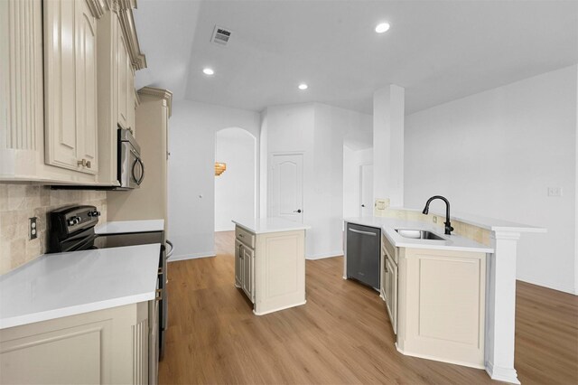 kitchen featuring cream cabinetry, a center island, appliances with stainless steel finishes, and sink