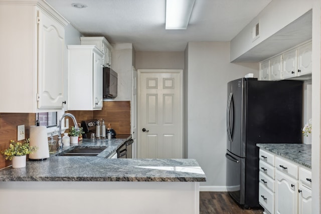 kitchen featuring sink, dark stone countertops, appliances with stainless steel finishes, white cabinetry, and kitchen peninsula