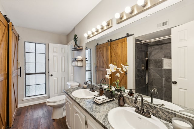 bathroom featuring hardwood / wood-style floors, a tile shower, and a wealth of natural light