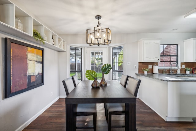 dining space with dark hardwood / wood-style floors, sink, and a chandelier