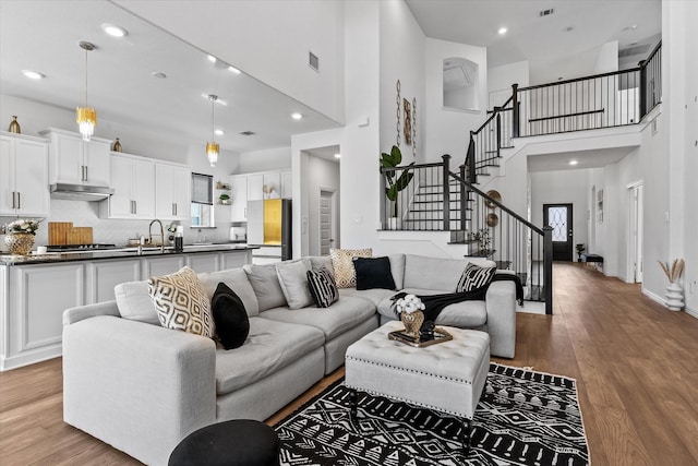 1307 Wheelwright Dr, Forney, TX 75126 - living room featuring a towering ceiling, stairway, wood finished floors, and recessed lighting