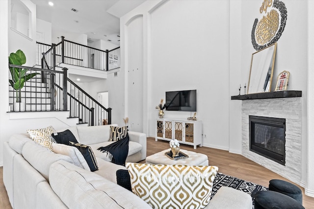 living room with a fireplace, a high ceiling, and light hardwood / wood-style flooring