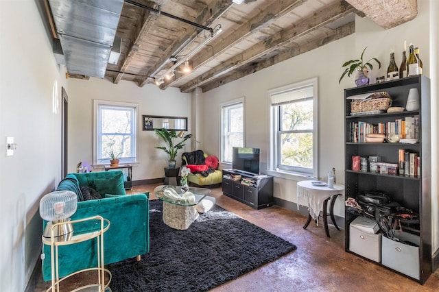 sitting room with a healthy amount of sunlight, concrete flooring, and beam ceiling