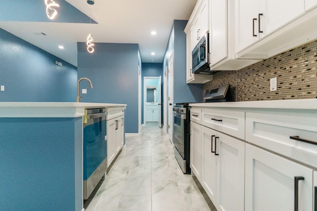 kitchen featuring decorative backsplash, white cabinets, pendant lighting, and appliances with stainless steel finishes