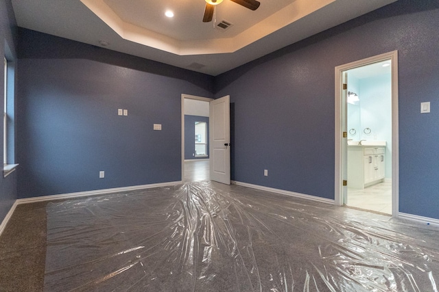 empty room with ceiling fan, sink, and a raised ceiling