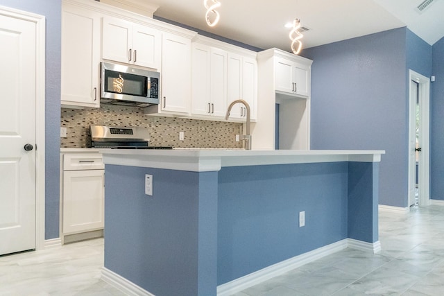 kitchen with tasteful backsplash, a kitchen island, stainless steel appliances, and white cabinetry