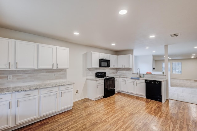 kitchen featuring light wood-type flooring, tasteful backsplash, sink, black appliances, and white cabinets