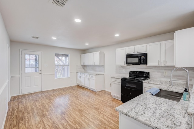 kitchen with decorative backsplash, light wood-type flooring, sink, black appliances, and white cabinetry