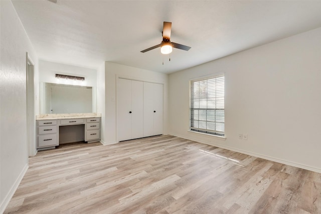 unfurnished bedroom featuring a closet, light hardwood / wood-style floors, ceiling fan, and ensuite bathroom