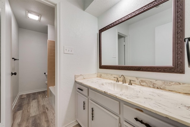 bathroom with a textured ceiling, vanity, hardwood / wood-style flooring, and shower / bathtub combination