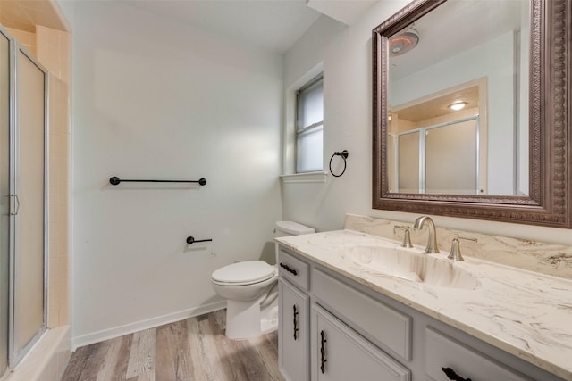 bathroom featuring wood-type flooring, vanity, toilet, and walk in shower