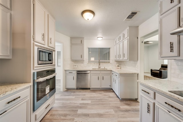 kitchen featuring white cabinetry, sink, stainless steel appliances, tasteful backsplash, and light hardwood / wood-style flooring