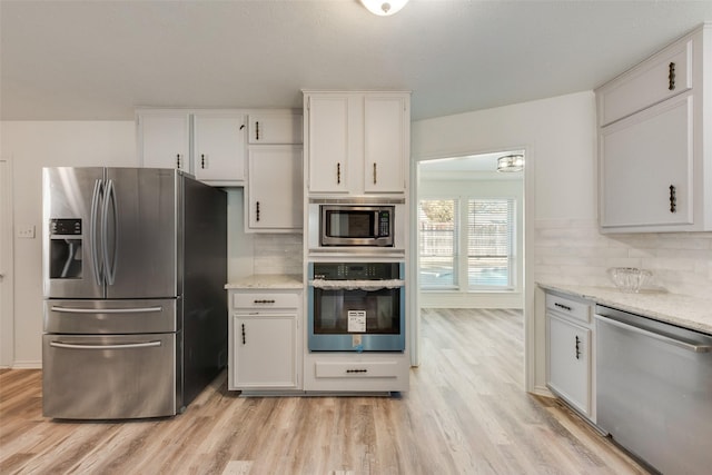 kitchen with backsplash, white cabinetry, stainless steel appliances, and light hardwood / wood-style flooring