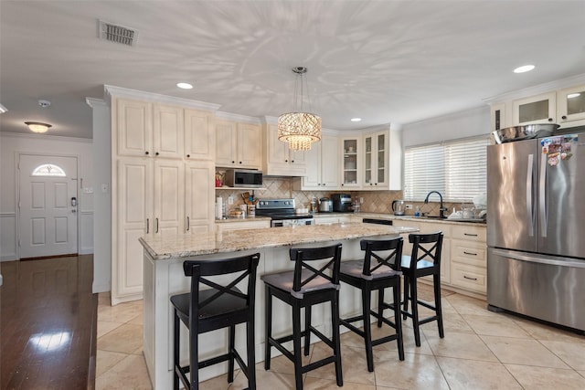 kitchen featuring crown molding, decorative light fixtures, stainless steel appliances, and a kitchen island