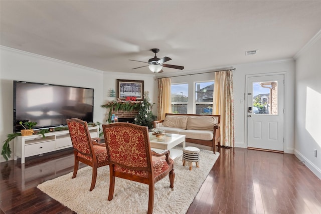 living room with crown molding, a brick fireplace, dark hardwood / wood-style floors, and ceiling fan