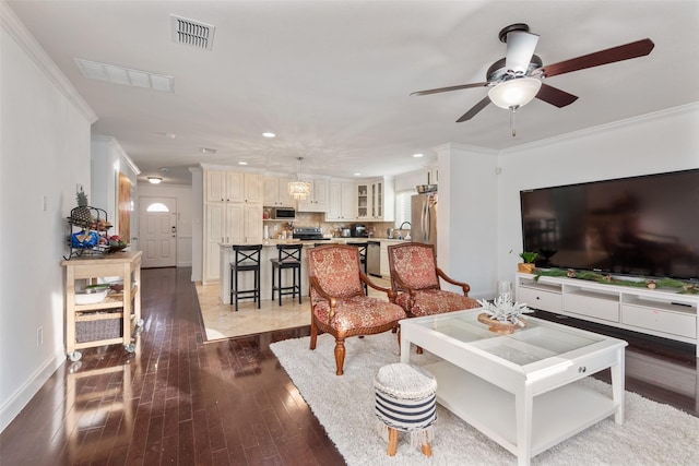 living room with hardwood / wood-style floors, crown molding, sink, and ceiling fan