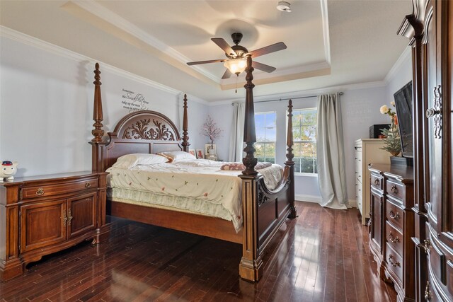 bedroom featuring dark hardwood / wood-style flooring, ornamental molding, ceiling fan, and a tray ceiling