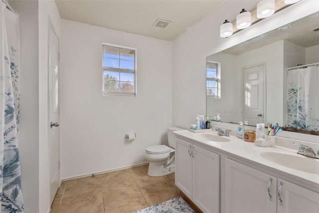 bathroom with tile patterned floors, vanity, toilet, and a wealth of natural light