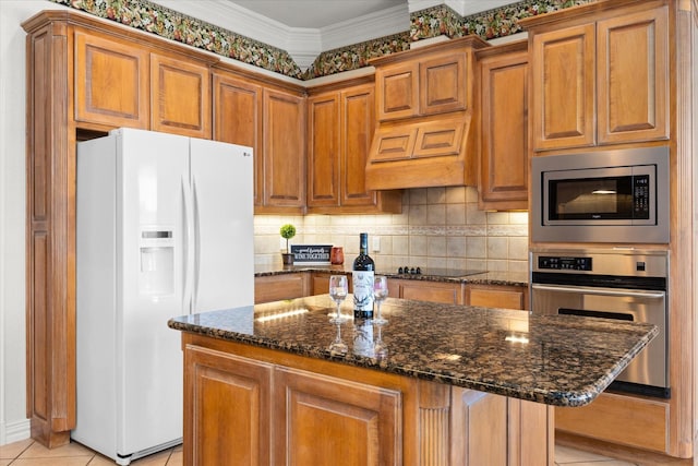 kitchen featuring a center island, crown molding, dark stone countertops, light tile patterned floors, and stainless steel appliances