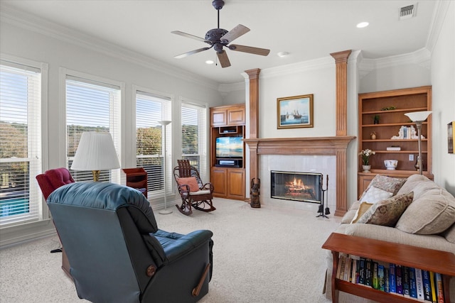 living room with a tile fireplace, crown molding, ceiling fan, and light colored carpet